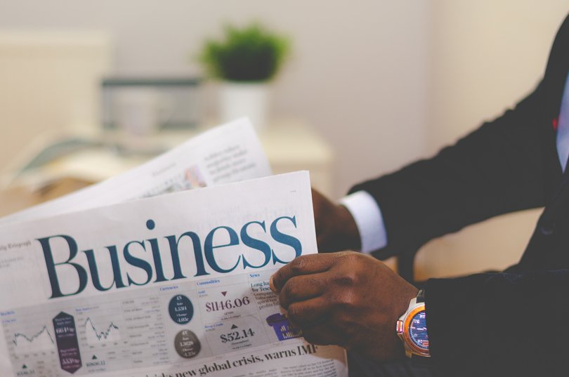 Black man in a dress suit holding the business section of the news paper